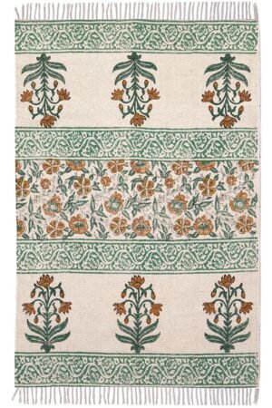 Overhead view of an elegant floral washable cotton rug featuring green and terracotta botanical motifs on a cream base. Close-up of the knotted fringe detail and sage green patterned border on a flatweave washable cotton rug. Botanical print washable cotton rug with an Indian-inspired block print design laid flat on a hardwood floor.